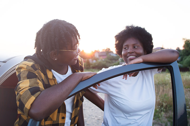 Two women standing next to a car